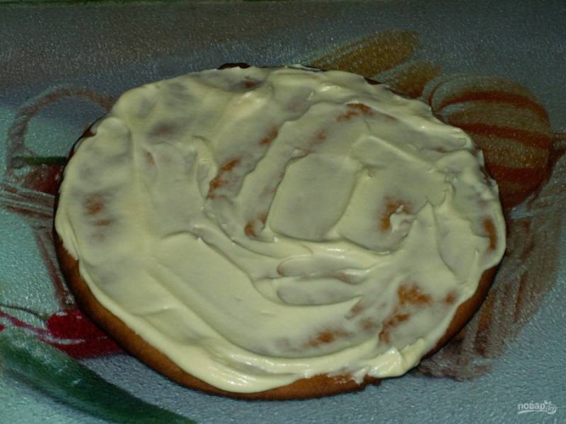 Соберите торт на ровной поверхности: выложите первый корж на блюдо и смажьте равномерно кремом. 