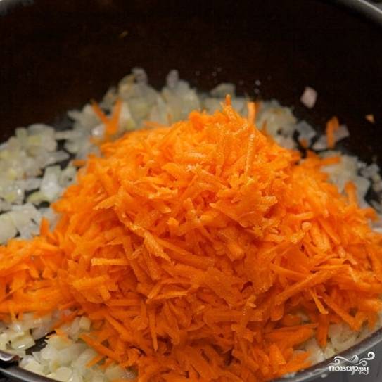 Морковь натираем на терке и добавляем к луку и чесноку. Перемешиваем и готовим на умеренном огне еще 7-10 минут.