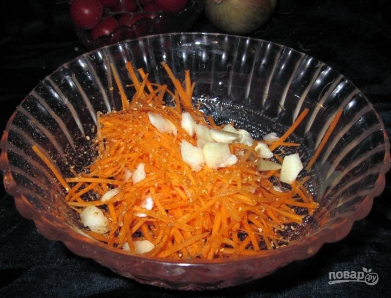 В другой миске соедините чеснок, нарезанный кусочками, крупно натёртую морковь и помидоры, нарезанные кружочками. 