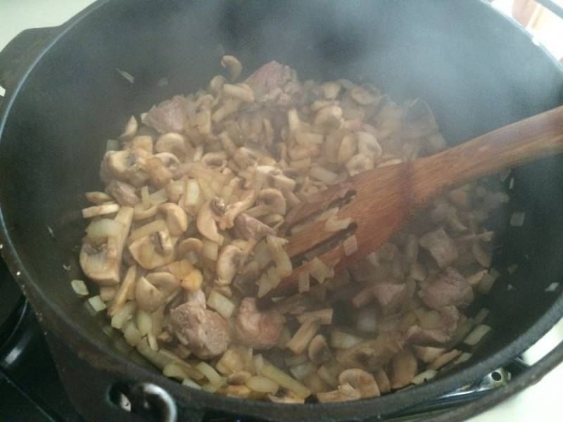 3.	Добавьте в казанок к мясу и луку грибы, перемешайте и готовьте до испарения жидкости.