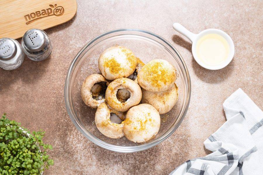Выложите шляпки в глубокую миску, добавьте соль, черный молотый перец и универсальную приправу. Влейте растительное масло.