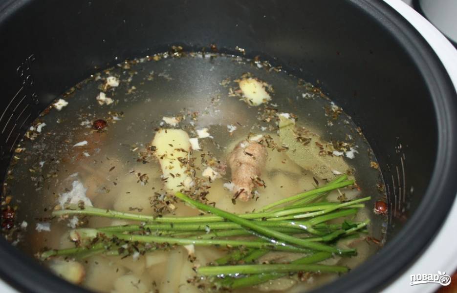 В чашу мультиварки вливаем куриный бульон, добавляем зелень, порезанный картофель и специи. Устанавливаем режим "Тушение" 1 час.