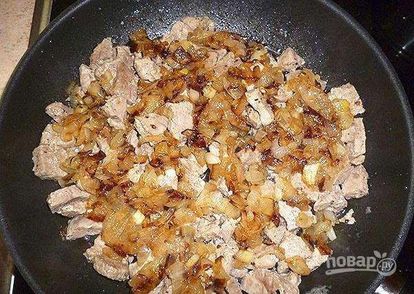 Почти к готовому мясу добавьте лук и бананы. Закройте блюдо крышкой, тушите его ещё 5 минут.