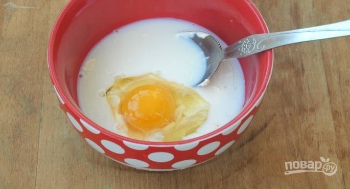 В отдельную пиалу вбейте сырое куриное яйцо. Добавьте к нему сметану и влейте молоко. Взбейте ингредиенты вилочкой, чтобы они стали однородными. 