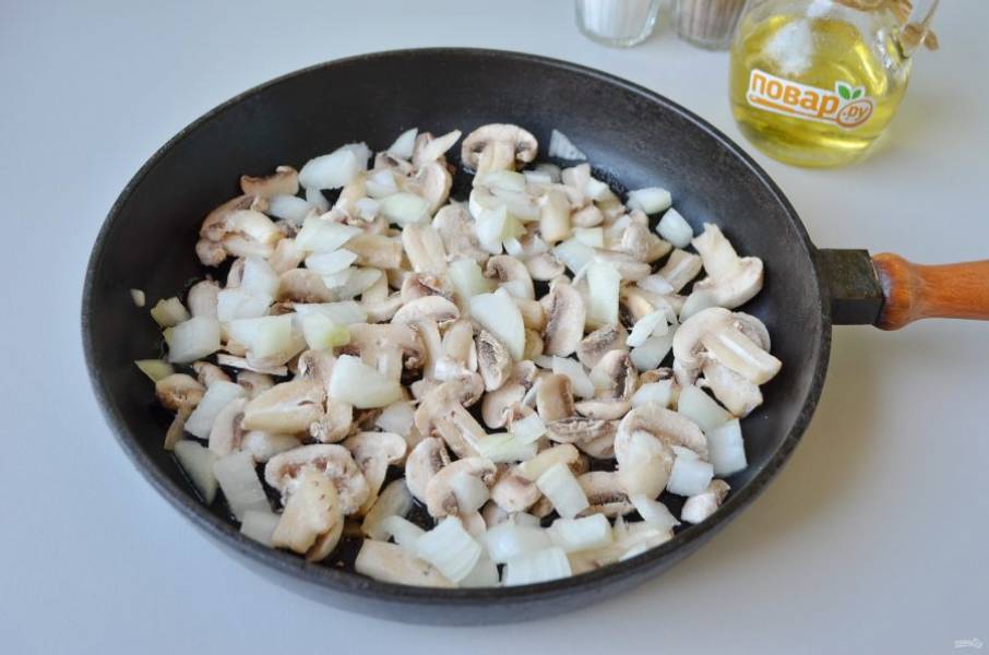 2. Порежьте мелко лук, если грибы свежие, то вымойте, порежьте мелко. Налейте растительное масло в сковороду, положите грибы, лук и посолите. Жарьте до готовности.