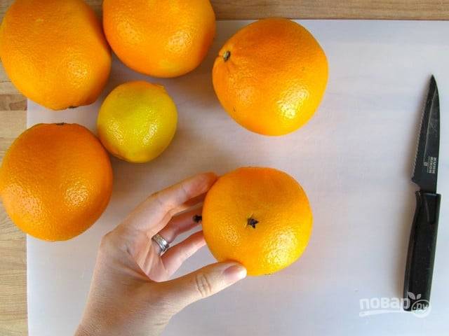 В каждом апельсине и в одном лимоне сделайте маленьких 5 проколов. Во все вставьте гвоздику. Отправьте фрукты запекаться на противне на 70 минут.