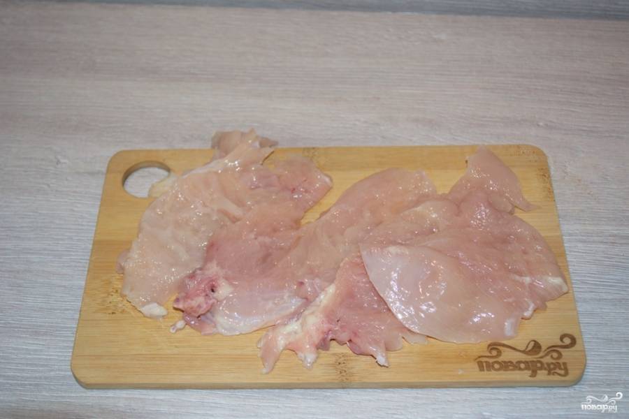 Куриное филе отделим от тушки курицы. Чистое филе без кожи нарежем на небольшие пластины. Каждую пластинку мяса накроем пищевой пленкой и отобьем молоточком для мяса. Использование пленки позволяет не допустить дыр в мясе.