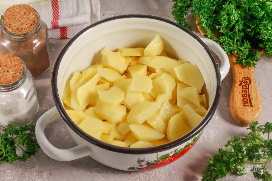 Картофельные клубни нарежьте небольшими ломтиками и высыпьте нарезку в кастрюлю или в казан.