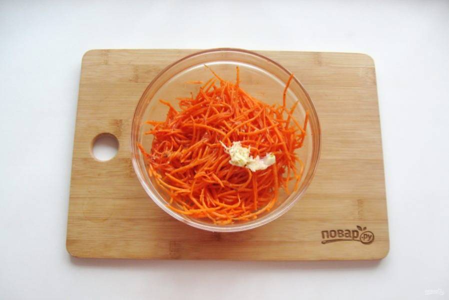 Через ситечко влейте горячее подсолнечное масло в морковь. Жареный лук здесь не нужен. Добавьте в морковь измельченный чеснок и перемешайте.