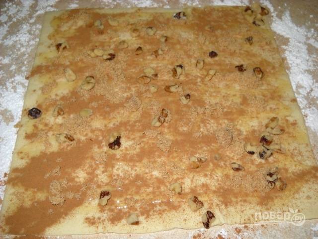1.	Заранее разморозьте слоеное тесто, посыпьте стол сахарной пудрой и разверните тесто в 2 пласта, немного раскатайте каждый (совсем немного). Смажьте оба пласта медом, посыпьте корицей, нарубленными грецкими орехами.