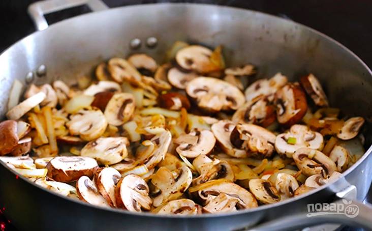 Уберите мясо, в сковороду положите оставшееся масло, измельчите лук и обжарьте минутку. Добавьте измельченный чеснок и порезанные грибы, жарьте минут 7-8.