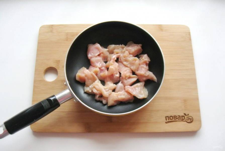 Куриное филе помойте, нарежьте небольшими кусочками и выложите в сковороду.