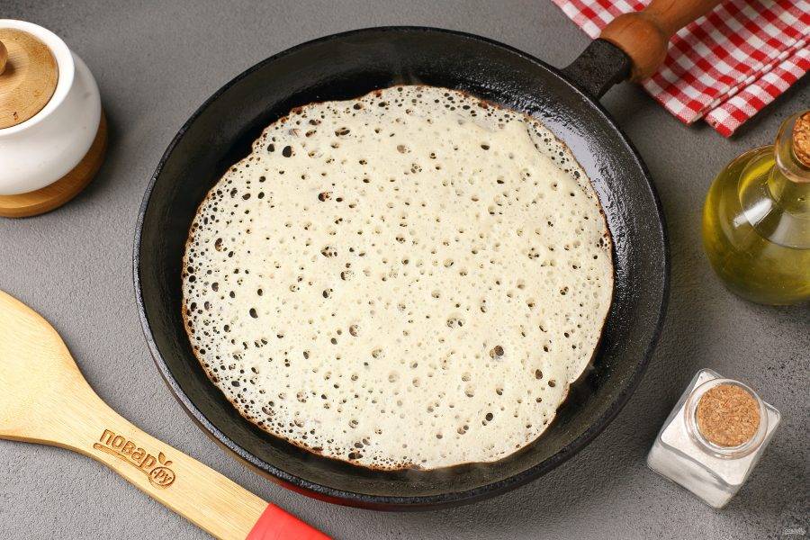 Сковороду разогрейте и смажьте маслом. Налейте половником тесто, равномерно распределяя его по всей сковороде. Тесто начнёт "дышать", т.е. появятся характерные поры-дырочки.