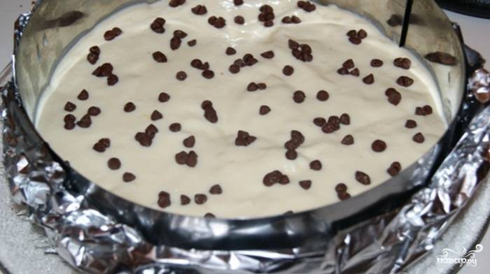 Поместите одну часть бисквита в форму с высокими бортиками. Натрите половину молочного шоколада. Выложите одну вторую часть крема на бисквит и посыпьте шоколадом.