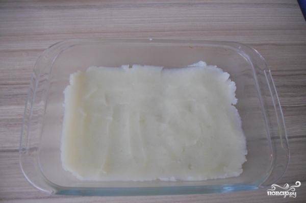 2. Картофельное пюре разделите на две части. Смажьте форму растительным маслом. Выложите в неё одну часть пюре. Разровняйте.