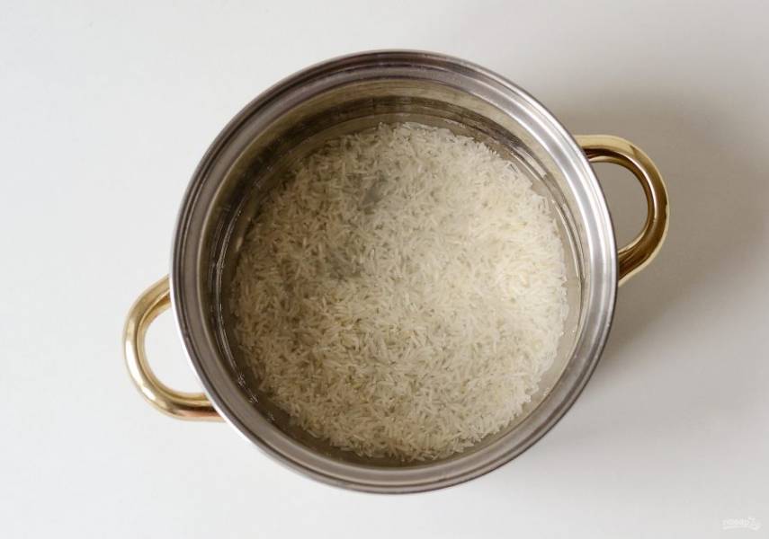 Рис промойте в холодной воде до прозрачности. Переложите в кастрюлю, залейте водой так, чтобы она покрывала рис на 1 см. Посолите. Доведите до кипения, затем варите на медленном огне 15 минут. 
