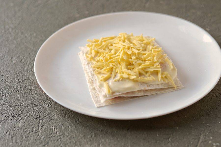 Следующий слой сделайте из сыра, затем накройте последним кусочком лаваша. Аналогично поступите с остальным лавашом. 