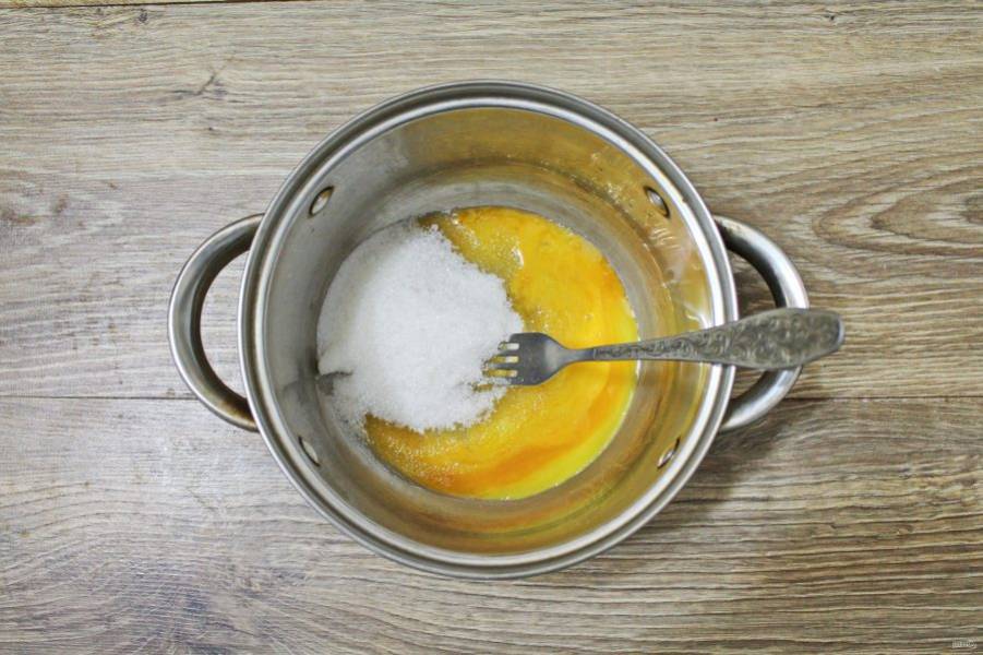 В кастрюлю выложите яичный желток, всыпьте сахар и тщательно разотрите.