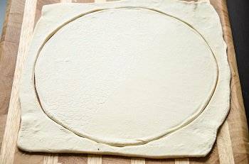 За это время слоеное тесто уже должно разморозиться. Раскатываем его до толщины 6 мм, вырезаем круг, кладем на противень.