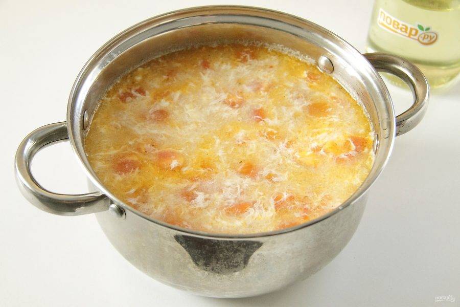 Размешивая кипящий суп ложкой по кругу, влейте тонкой струйкой яйца из миски.