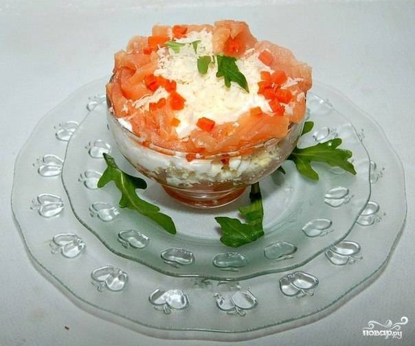 Украсьте салат сметаной, посыпьте сыром. Добавьте сверху немного рыбы и моркови для украшения. Поставьте салат в холодильник на 2 часа, а затем подавайте к столу. 