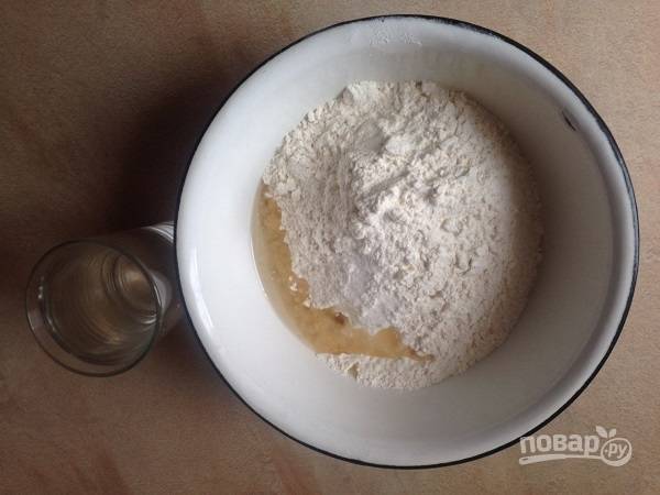 Просеиваем в миску муку, добавляем соль и растительное масло. Наливаем воду, замешиваем тесто.