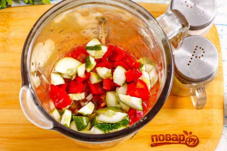 Влейте томатную массу в чашу блендера или в глубокую емкость, если будете использовать погружной блендер. Всыпьте туда же овощные нарезки. Очистите пару зубчиков чеснока и добавьте в емкость. Всыпьте соль и молотый черный перец.