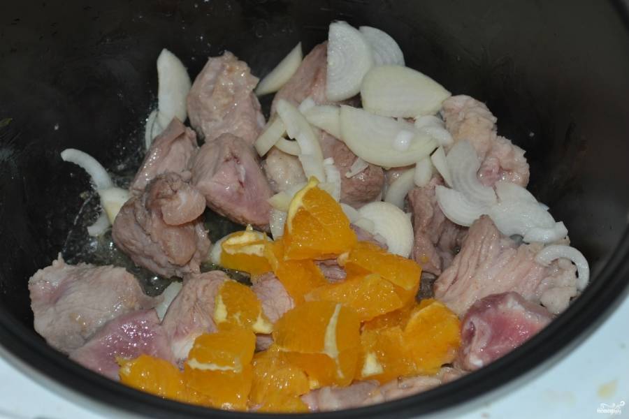 В чашу мультиварки влейте пару ложек растительного масла и выложите мясо. Включите режим обжарки на 15 минут. Обжаривайте мясо 10 минут, затем добавьте лук, а через пару минут и апельсин, готовьте до конца работы программы. 