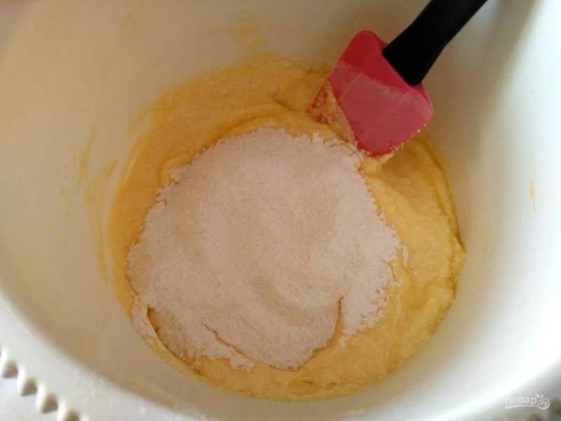 Отдельно соедините муку с разрыхлителем и, просеивая смесь, постепенно всыпьте её во взбитую масляно-яичную массу. Перемешивайте тесто снизу вверх ложкой или силиконовой лопаткой.