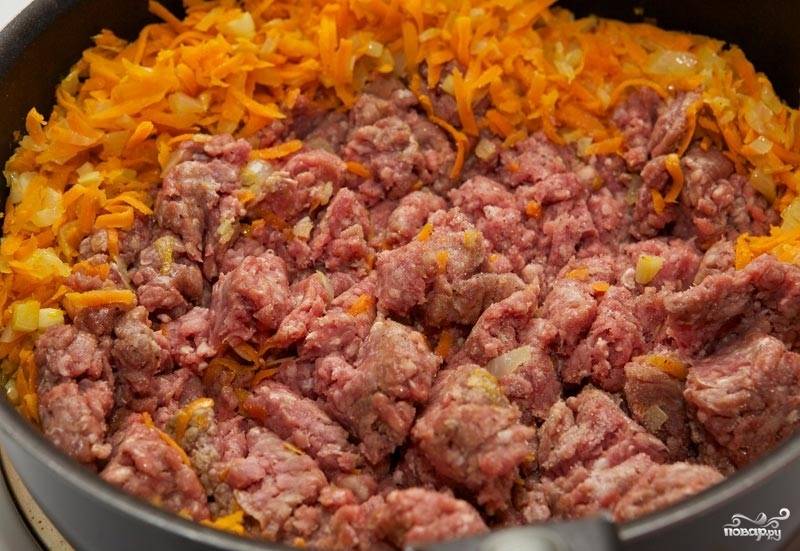 2. Добавьте измельченный чеснок и натертую на терке морковь. Следом выложите фарш. Это может быть как говяжий или свиной, так и куриный, например. 