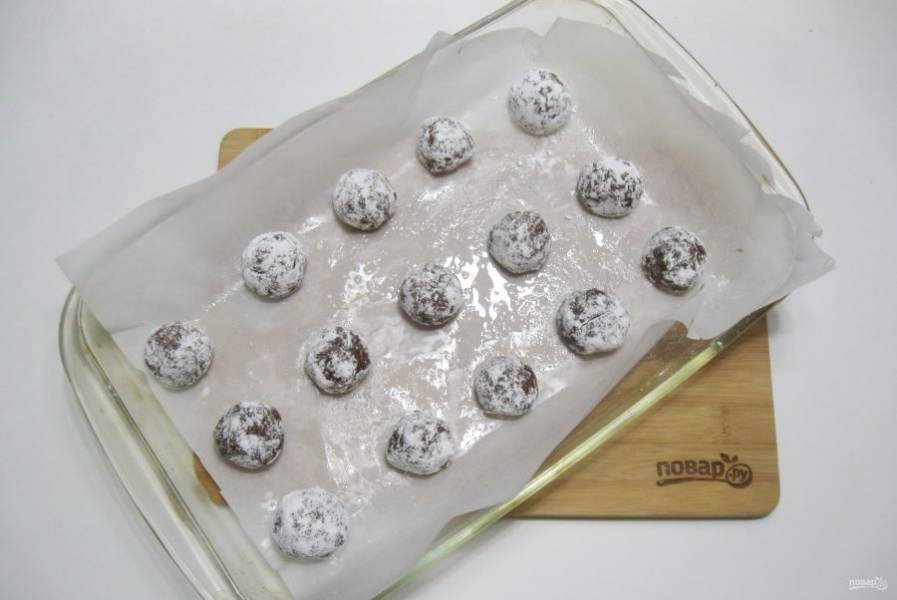 Обваляйте шарики из теста в сахарной пудре и выложите в форму для выпекания.