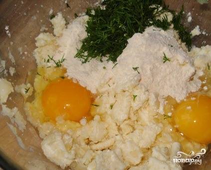 Картофель очистите, порежьте на куски и отварите до полной готовности. При помощи толкушки сделайте из него пюре. Выложите пюре в пиалку. Добавьте к нему перетертый через сито творог, мелко нарубленный укроп, соль, муку, разрыхлитель, вбейте два яйца. 