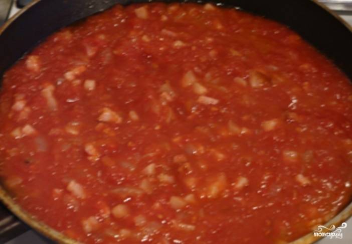 5. Очищенные от шкурки томаты в собственном соку добавьте к грудинке с луком. Дайте возможность закипеть на большом огне. 
