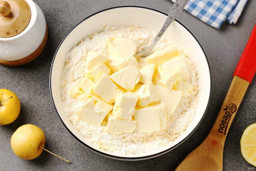 Соедините муку, соль и тёртый на мелкой тёрке сыр. Перемешайте и добавьте нарезанное кусочками масло.