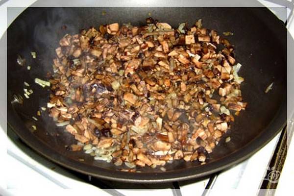 В сковороде на среднем огне нагрейте 2 ст.л. оливкового масла и обжарьте репчатый лук, нарезанный тонкими полукольцами, в течение 3 минут, а затем добавьте нарезанные грибы. Тушите грибы с луком еще 7 минут.