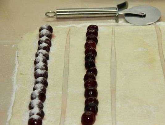 На полоску из теста выложите вишни без косточек в ряд и посыпьте сахаром. 