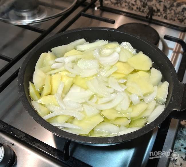 2.	Разогрейте сковороду с растительным маслом, выложите картошку и лук, обжаривайте их несколько минут, практически до готовности, но не подрумянивайте. 