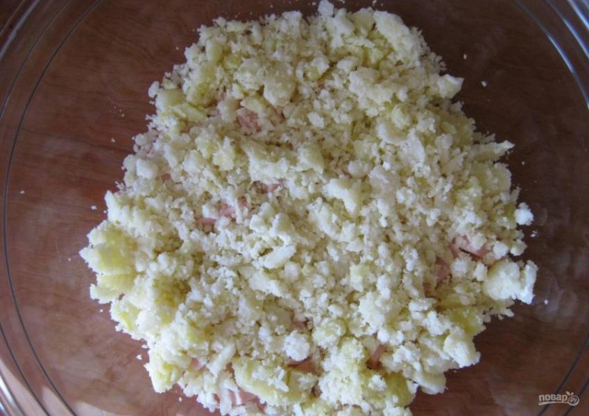 8.	Поверх колбасы выкладываю размятый картофель, распределяю и солю немного.