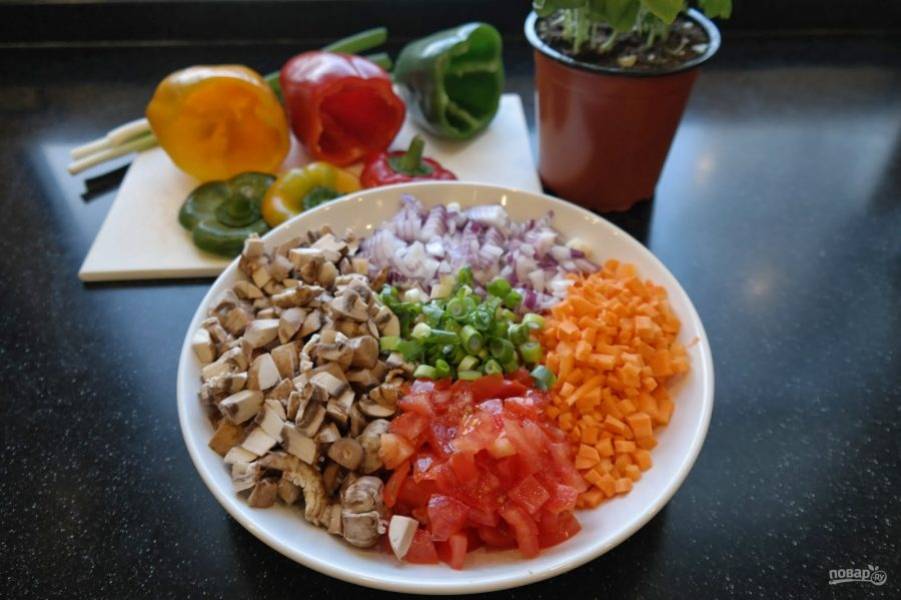 2. Грибы, лук, морковь, помидоры и зелень мелко нарежьте. На сковороде разогрейте растительное масло. Выложите лук, обжарьте его пару минут, после добавьте морковь, еще через 2-3 минуты выложите грибы. Обжарьте на среднем огне минут 5. У перцев срежьте верхушку и аккуратно удалите семена. 