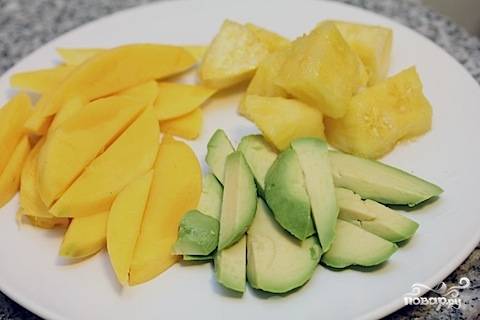 2. Очистите и нарежьте средними кусочками авокадо, ананас и манго. Нарежьте мелкими кубиками луковицу и сельдерей. Измельчите петрушку. 