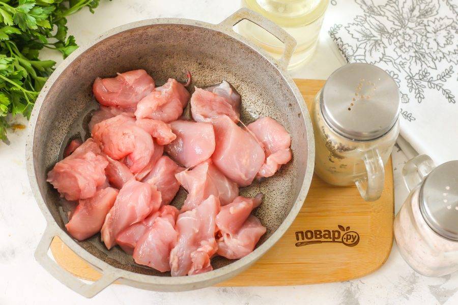 Промойте крыло индейки, срежьте кожу и пленки, срежьте мясо с костей и нарежьте мякоть на порционные кубики. Прогрейте растительное масло в казане и выложите в него кубики мяса. Обжарьте около 3 минут до румяности.