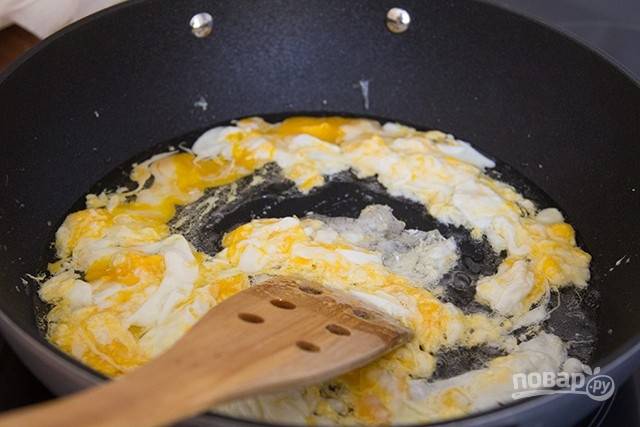 В воке или сковороде с антипригарным покрытием нагрейте подсолнечное масло, вбейте яйца и готовьте 1 минуту, интенсивно перемешивая.