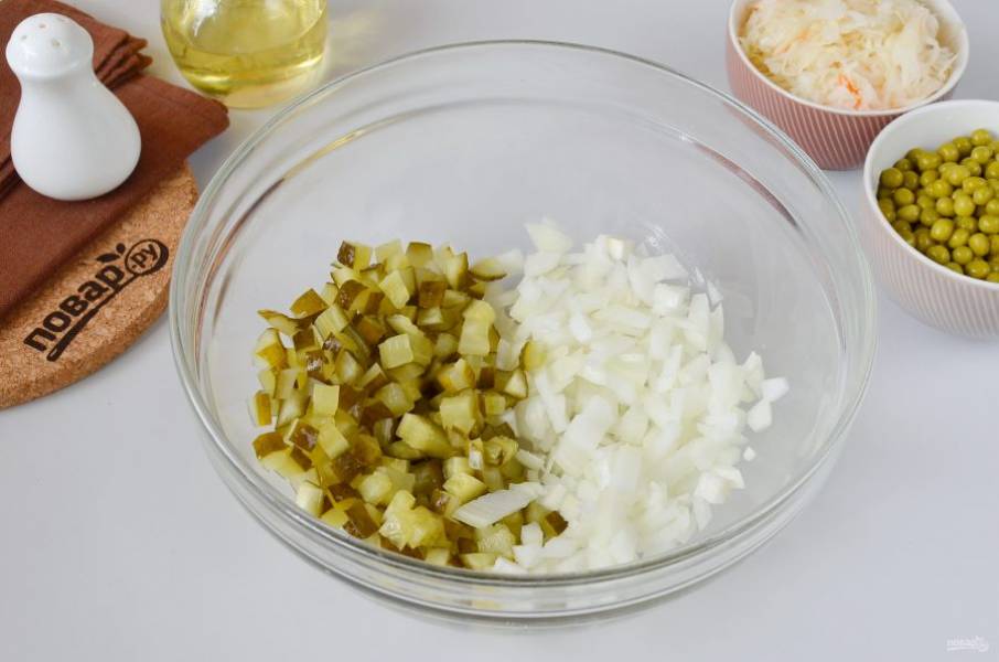 Очистите луковицу, мелко порежьте кубиками, как и огурец бочковой. Выложите в большой салатник.