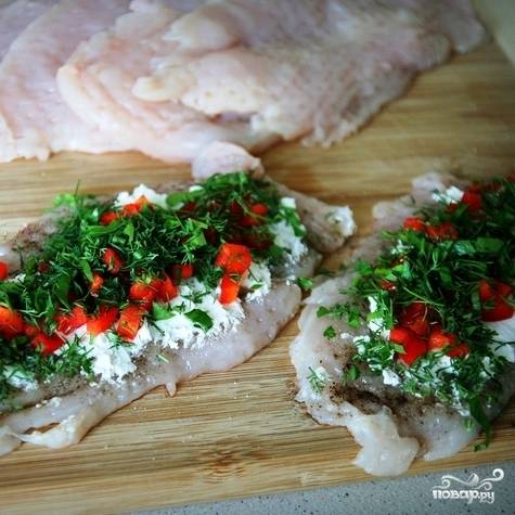 Далее посыпаем каждый кусочек куриного филе мелко нарубленной зеленью и кубиками нарезанным перцем.