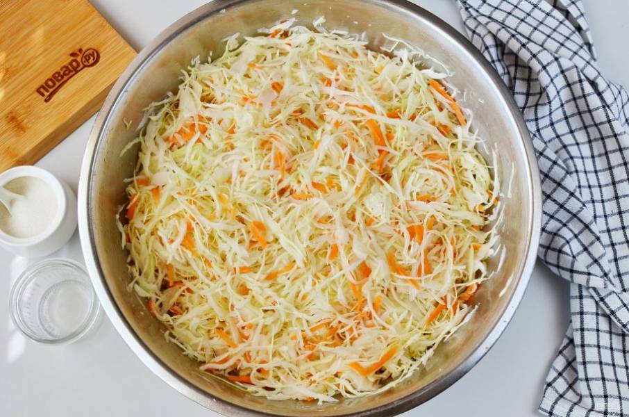 В большой миске перемешайте капусту с морковью, сахаром и солью, руками помните немного, чтобы овощи пустили сок. Оставьте минут на 10-15.