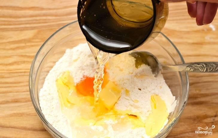 3. Вбейте желток, всыпьте сахар и влейте ледяную воду (сперва немного, по мере необходимости можно добавлять). Начните вымешивать тесто. 