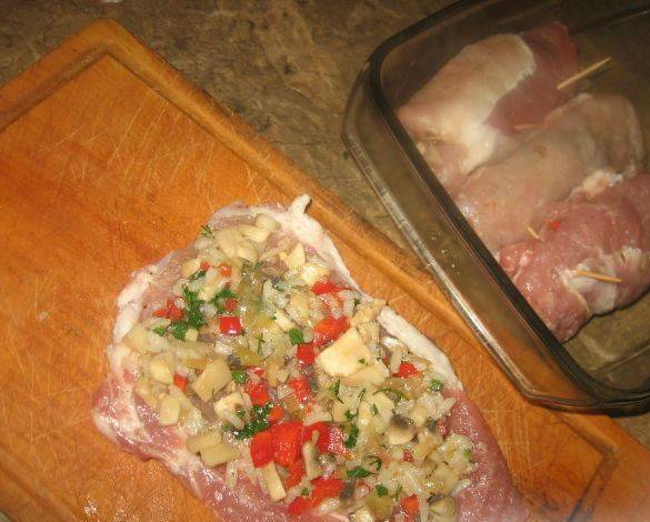 На каждый кусок свинины выкладываем по 2 ч.л. начинки, скручиваем мясо рулетиком.