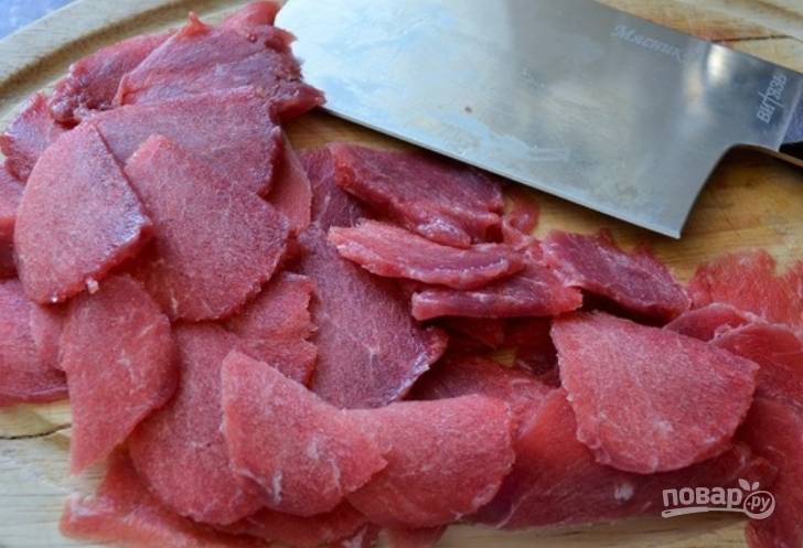 Слегка замороженную говядину нарезаем очень тонкими ломтиками. Лучше воспользуйтесь острым ножом.