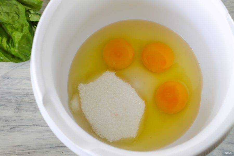В чашу кухонного комбайна или в глубокую емкость вбейте остальные куриные яйца и оставшийся белок. Всыпьте сахар и соль. Соль добавлять обязательно, она подчеркивает сладость выпечки. Взбейте все в пышную пену примерно 3-4 минуты.