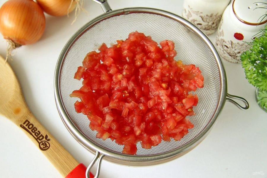 У помидора сделайте крестообразные надрезы ножом с двух сторон, залейте кипятком, после чего снимите шкурку и нарежьте мякоть мелкими кубиками. Откиньте нарезанные помидоры на сито, чтобы стекла вся лишняя жидкость.